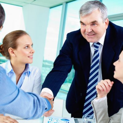 Agreement Photo of successful businessmen handshaking after striking deal with partners near by